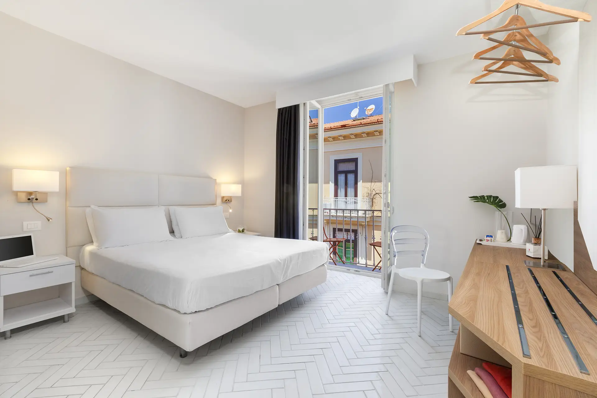 Camera d'albergo moderna e luminosa con letto matrimoniale e balcone.