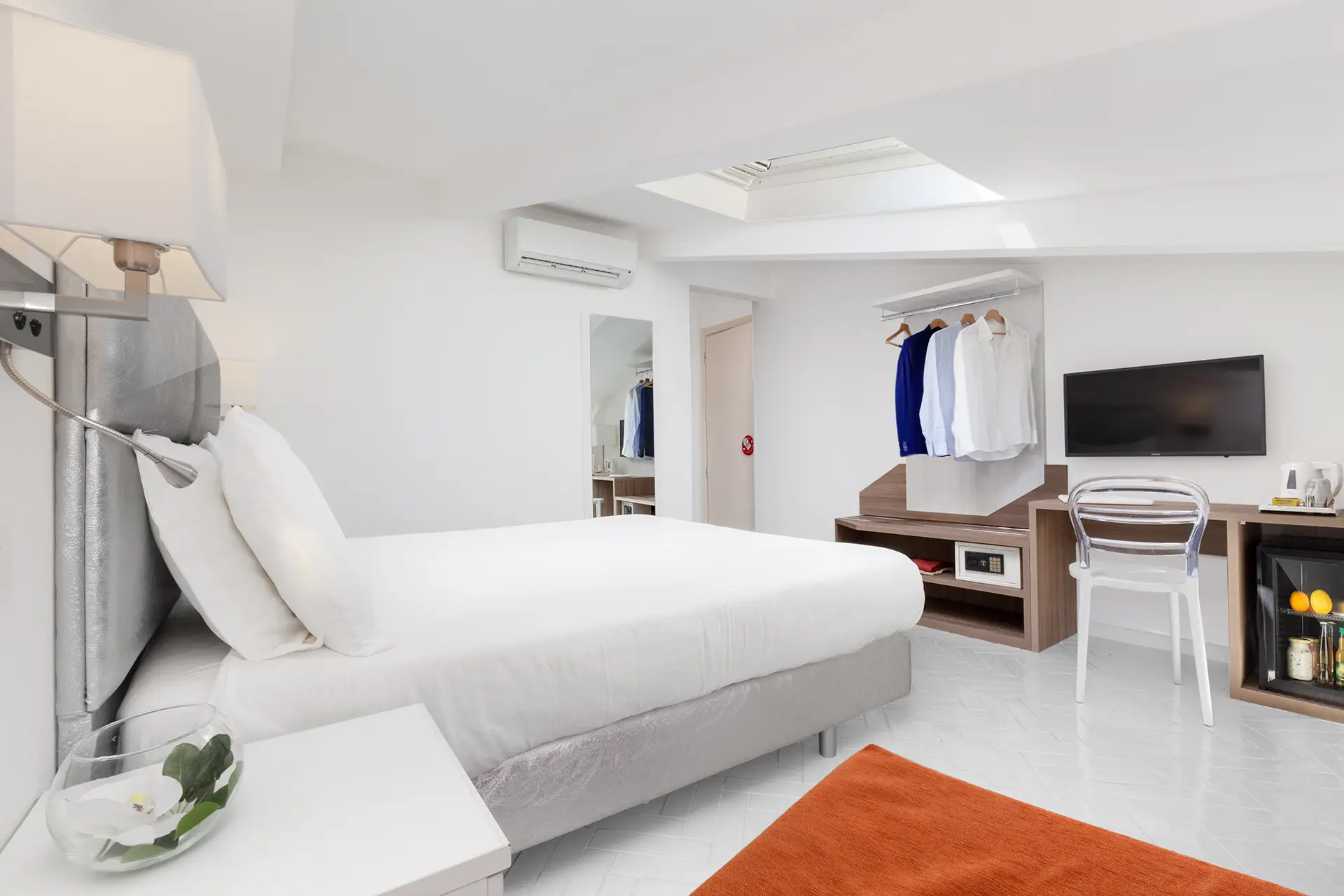 Camera da letto moderna e luminosa con letto matrimoniale, TV a parete e arredo minimalista.