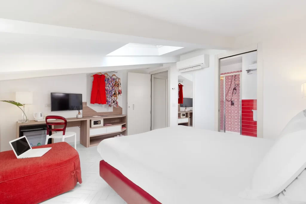 Camera da letto moderna con dettagli rossi e un bagno adiacente.