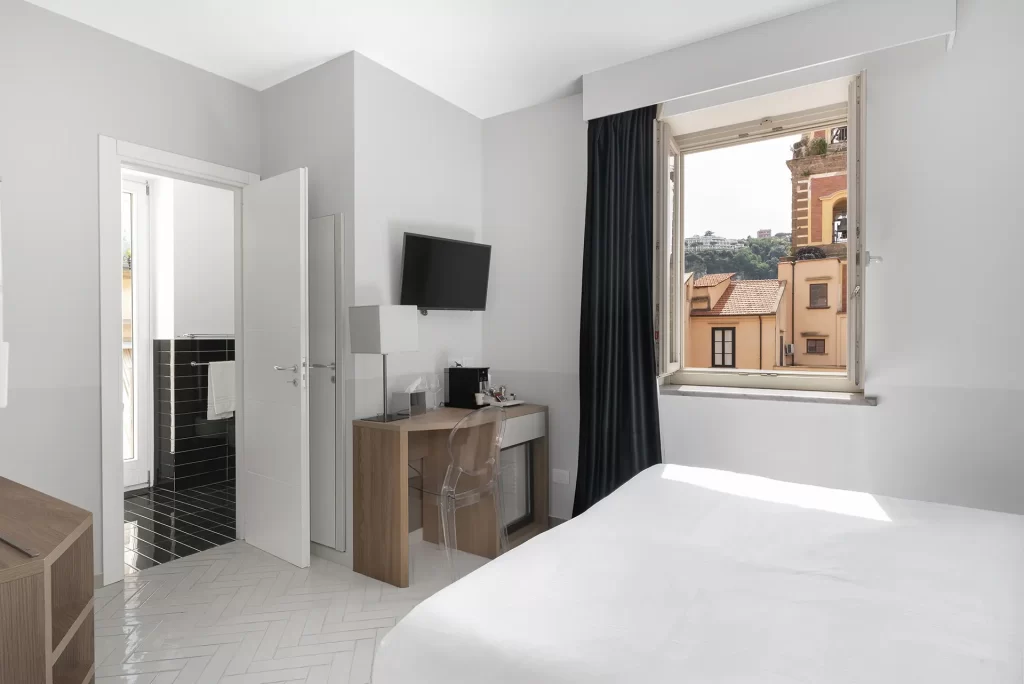 Camera d'albergo moderna con vista sulla città da una finestra aperta.