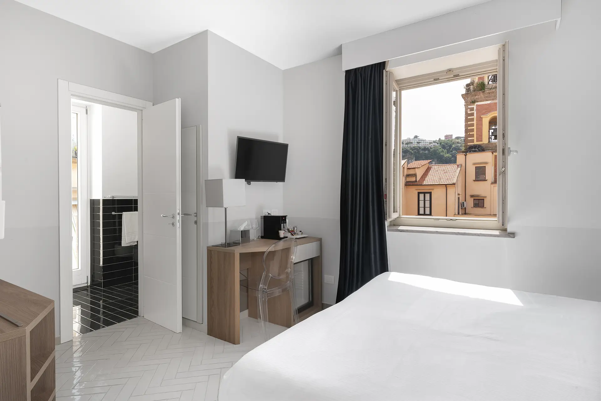 Camera d'albergo moderna con vista sulla città da una finestra aperta.