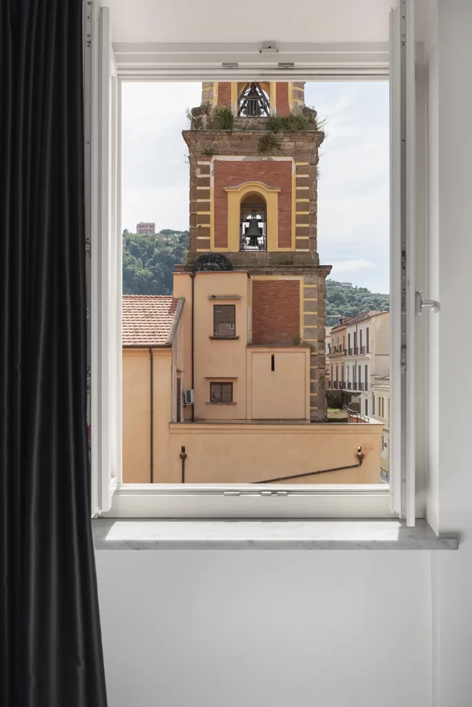 A view of a bell tower and buildings seen through an open window.