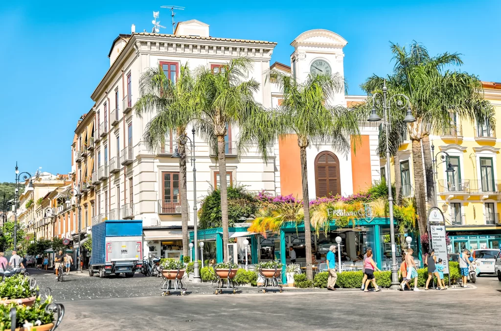Strada cittadina con edifici storici e palme sotto un cielo azzurro.