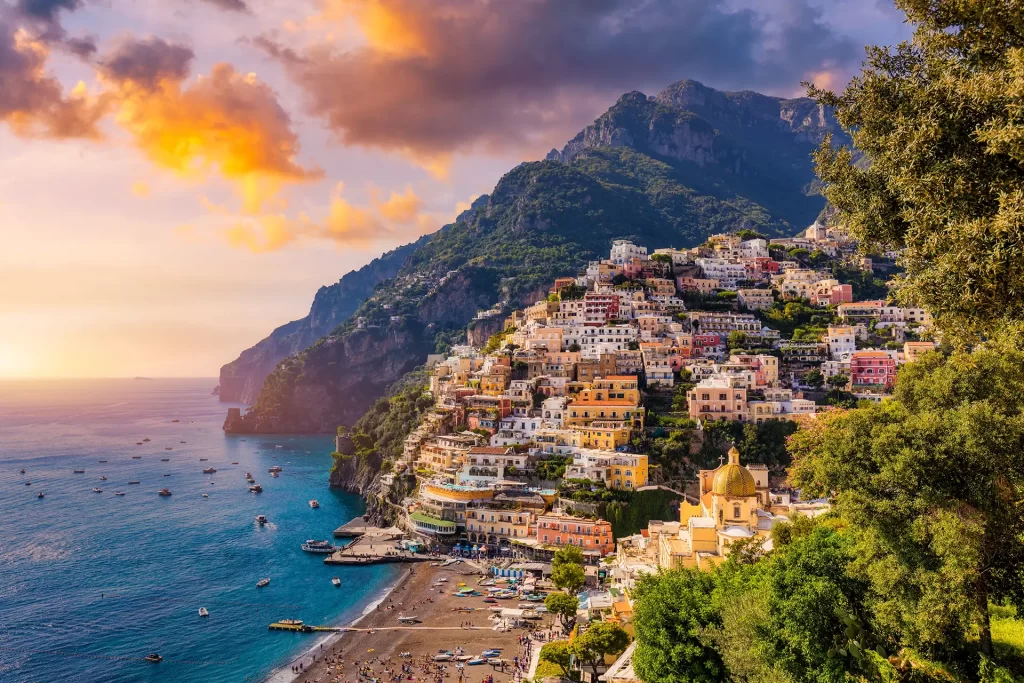 Panorama di Positano al tramonto sulla Costiera Amalfitana con case colorate e mare.
