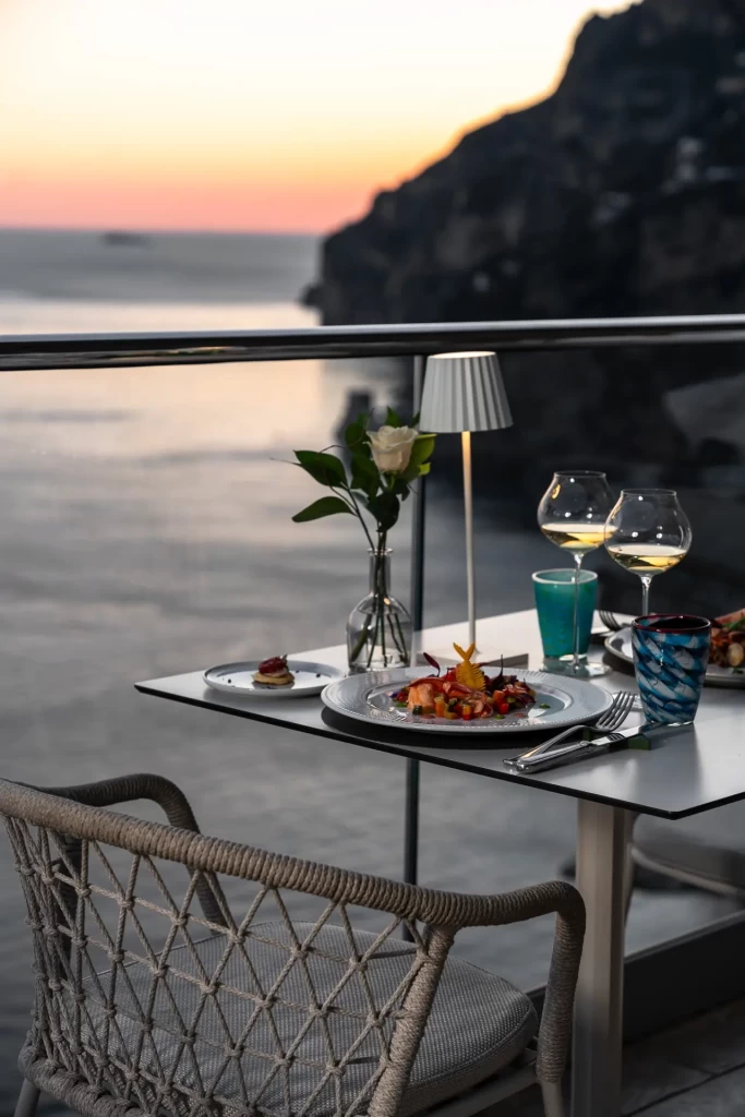 Cena elegante su una terrazza con vista al mare al tramonto.