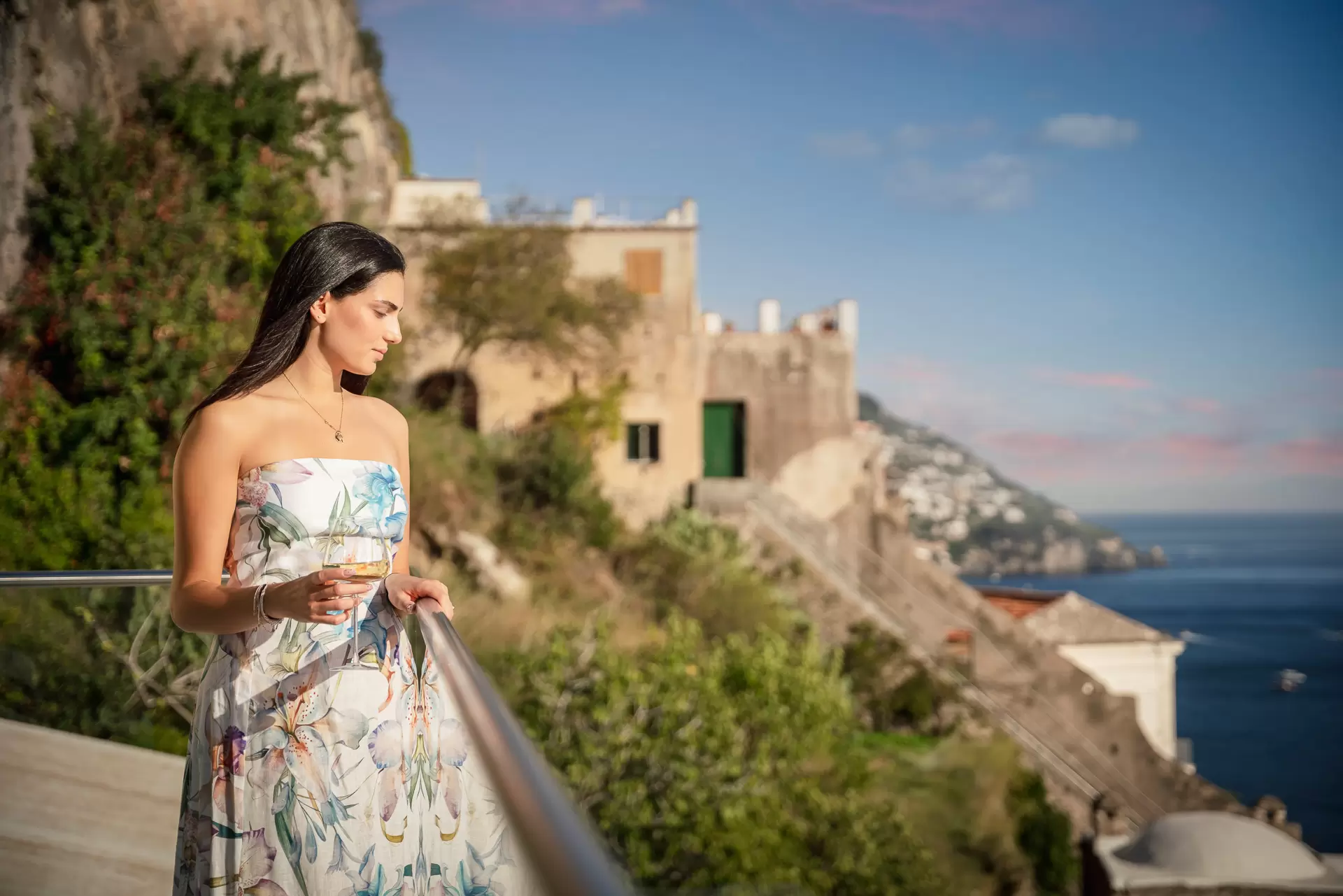 Donna su una terrazza panoramica con vista sul mare e paesaggio costiero.