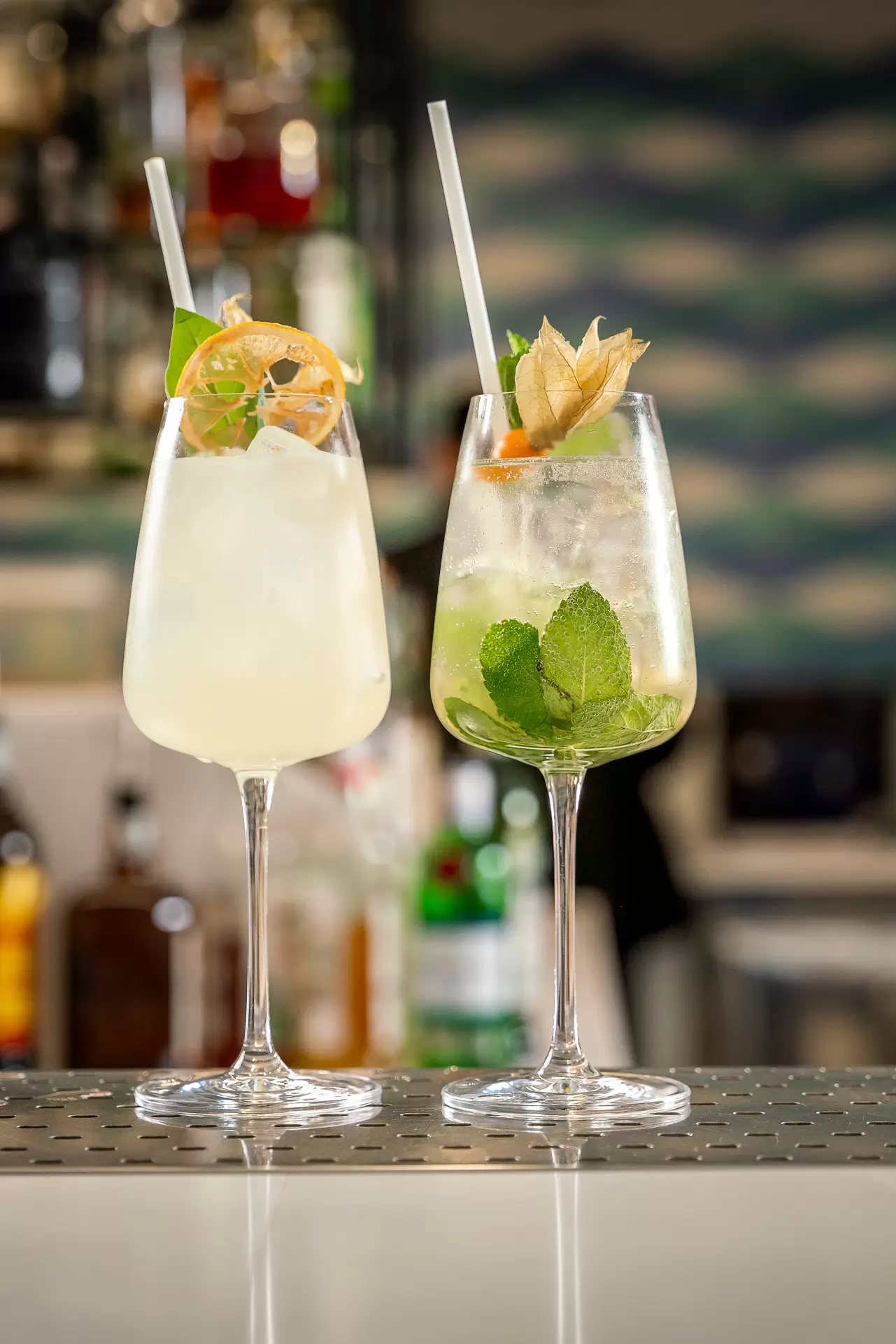 Due cocktail estivi su un bancone decorati con frutta e menta fresca.