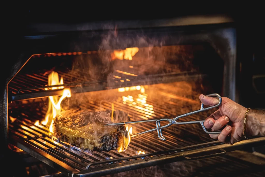 Carne alla griglia su barbecue con fiamma viva.