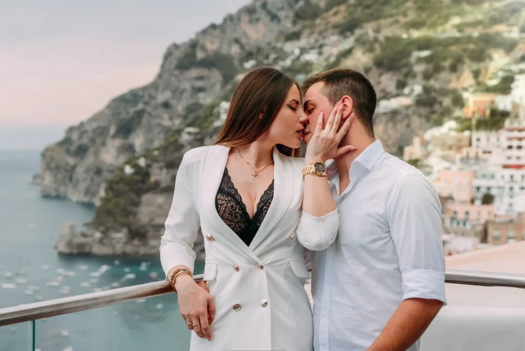Coppia che si bacia davanti a un panorama costiero mozzafiato.