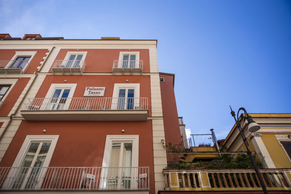 Facciata di un edificio rosso con balconi e cielo azzurro.
