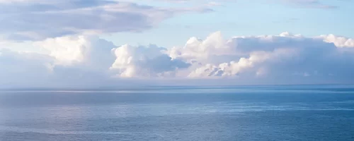 Barca solitaria su un mare calmo sotto un cielo parzialmente nuvoloso.