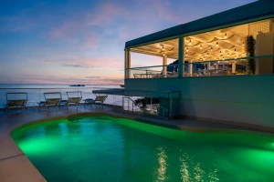 A serene poolside view at sunset with a lit indoor area.