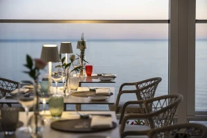 A restaurant table set for dining with a sea view at sunset.