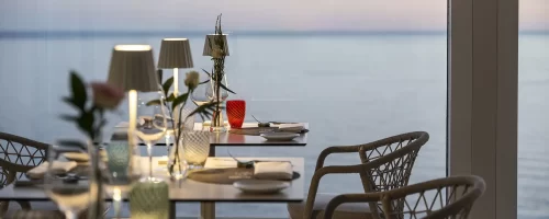 Sala da pranzo elegante con vista sul mare al tramonto.