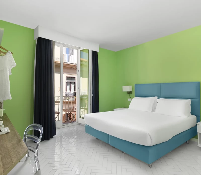 Camera da letto moderna con pareti verdi, letto matrimoniale e balcone.