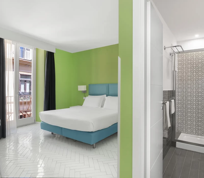 Camera d'albergo moderna con pareti verdi e bagno privato.