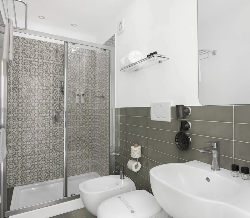 Bagno moderno con doccia dalle piastrelle decorate, lavabo e bidet.