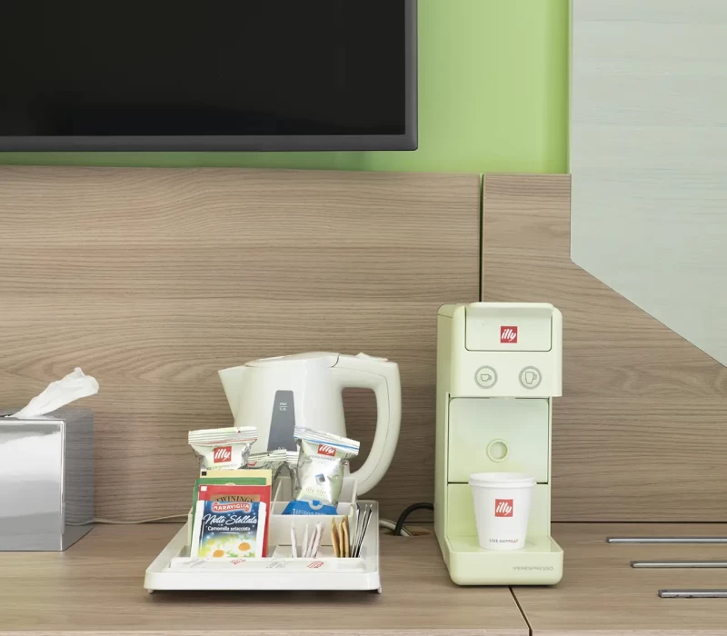 Angolo caffè con macchina espresso, bollitore e assortimento di tè e zucchero.