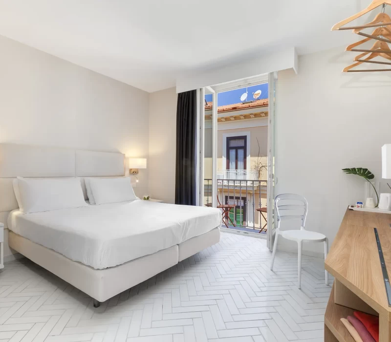 Camera d'albergo moderna e luminosa con letto matrimoniale e balcone.