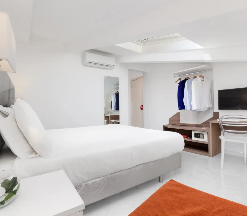 Camera da letto moderna e luminosa con letto matrimoniale, TV a parete e arredo minimalista.