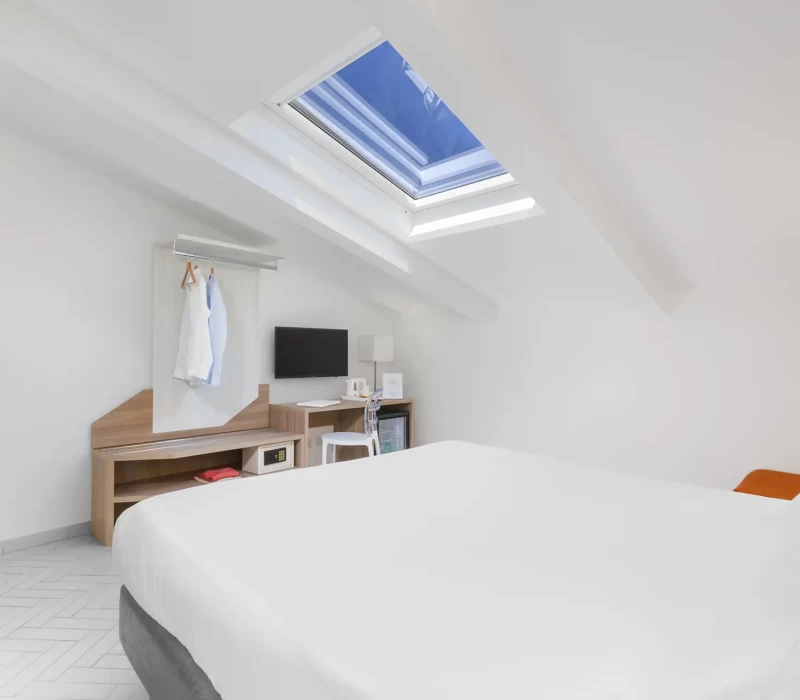 Camera da letto moderna con letto matrimoniale, lucernario e scrivania.