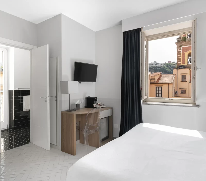 Camera d'albergo moderna con vista sulla città da una finestra aperta.