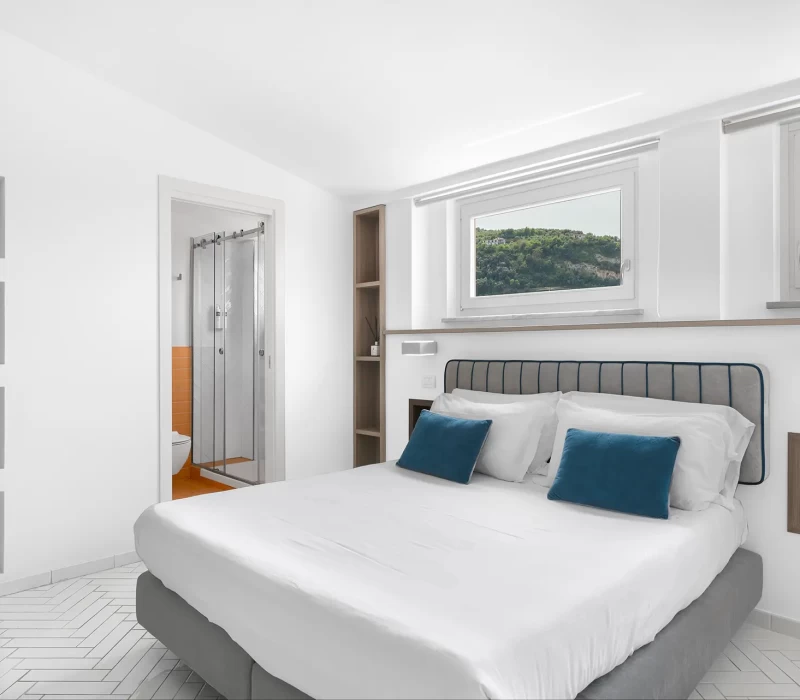 Camera da letto moderna e luminosa con bagno privato e finestra panoramica.