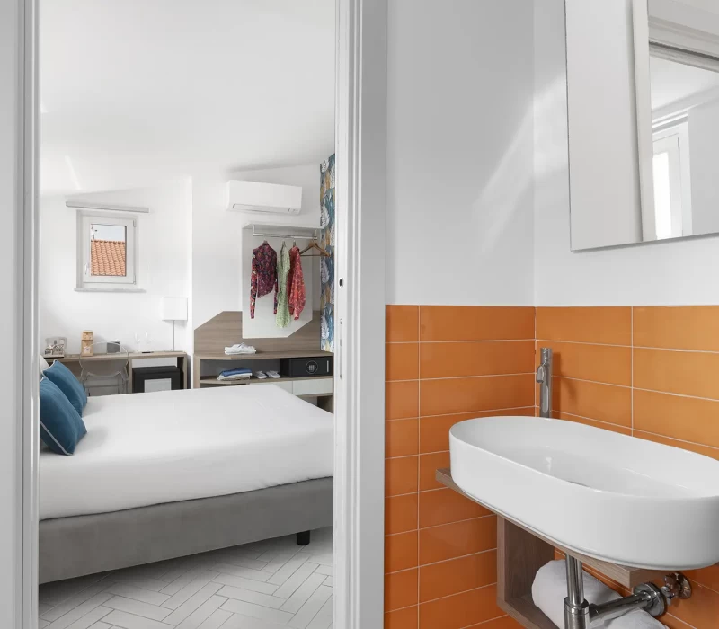 Vista di una camera d'albergo moderna con letto, bagno con lavabo e decorazioni colorate.