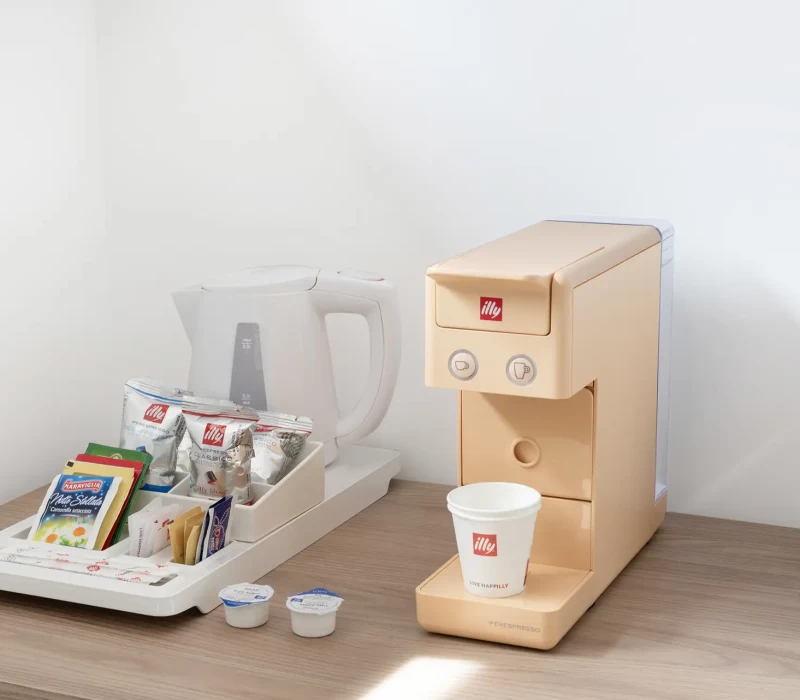 Macchina da caffè Illy con accessori per bevande su un tavolo di legno.
