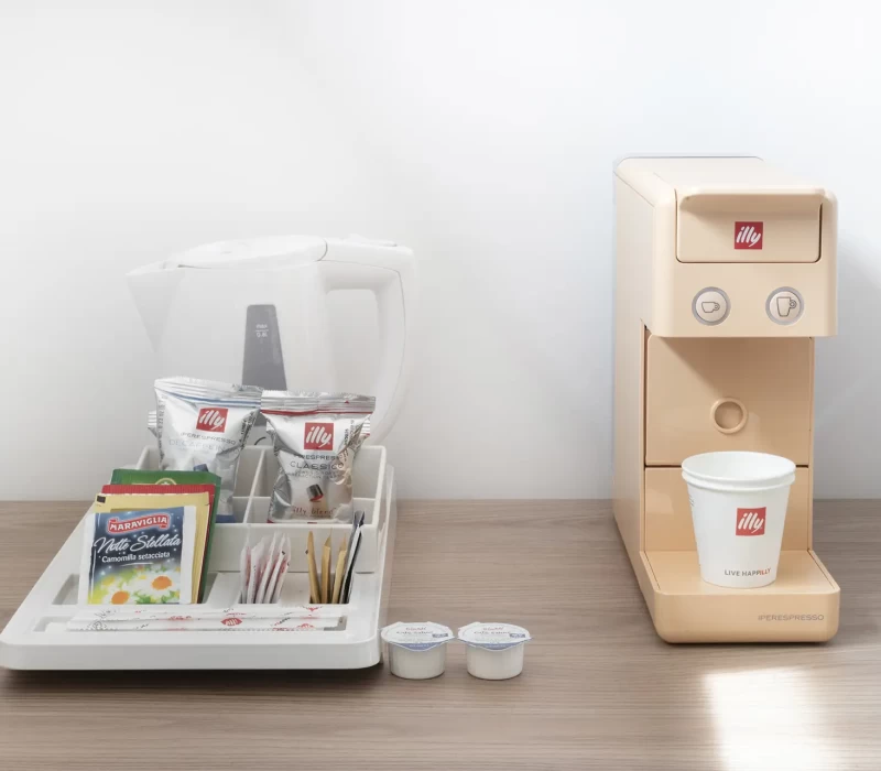 Set per tè e caffè su un tavolino con macchina da caffè Illy e accessori.