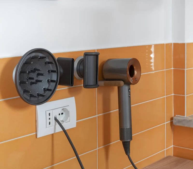 Asciugacapelli moderno montato su una parete con piastrelle arancioni.